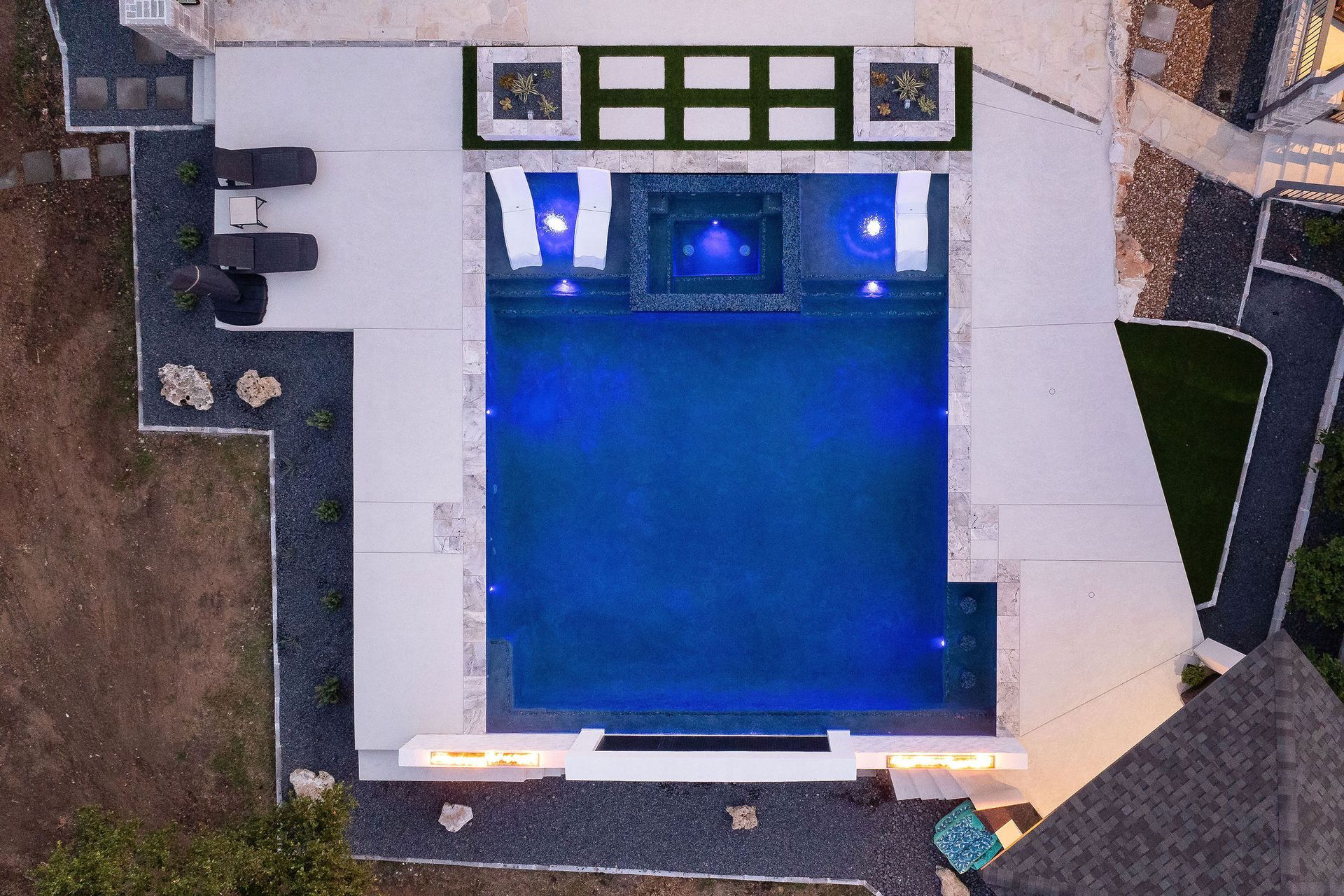 Luxury villa courtyard with lit swimming pool at sunset and surrounding white buildings