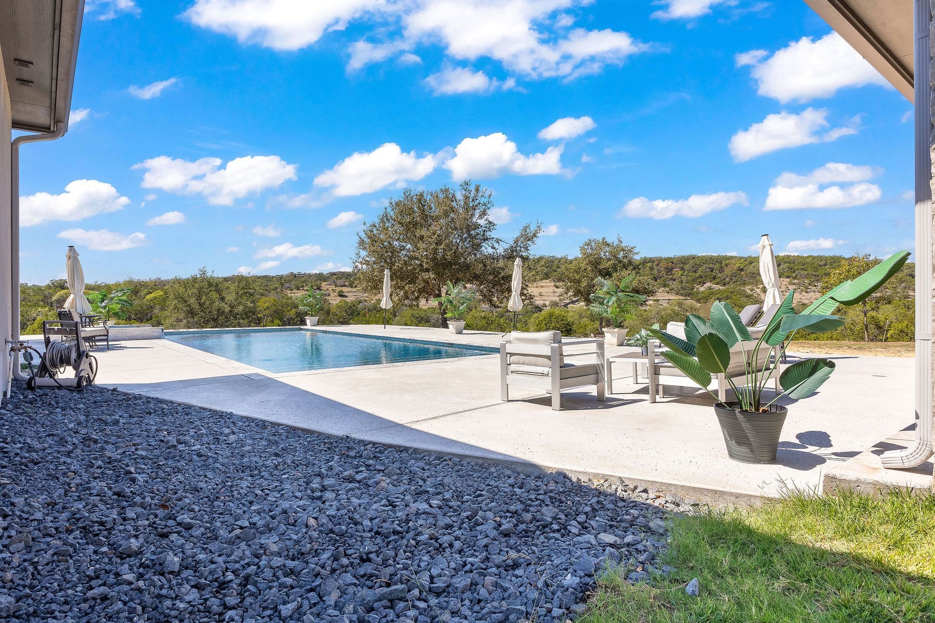 Luxury home with a covered patio beside a blue backyard swimming pool under a sunny sky
