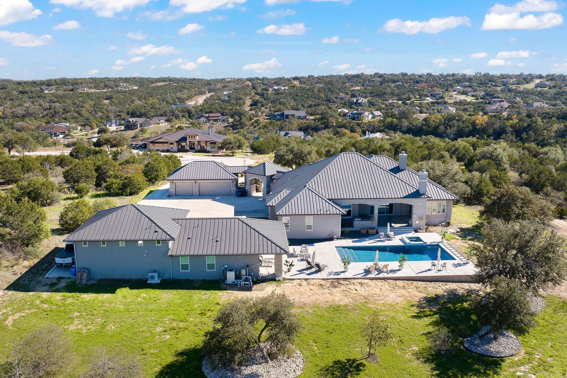 Luxury home with a covered patio beside a blue backyard swimming pool under a sunny sky