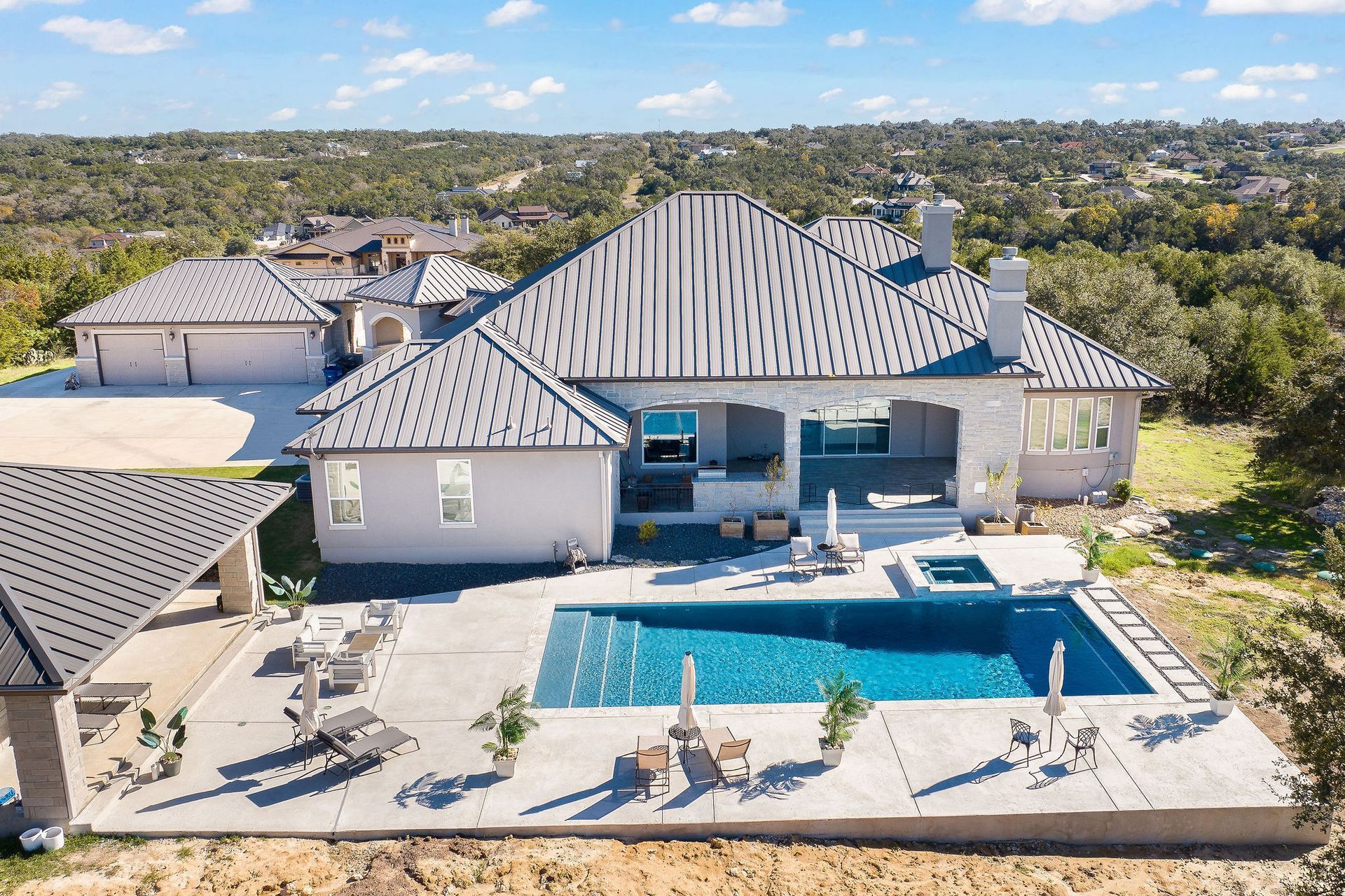 Luxury home with a covered patio beside a blue backyard swimming pool under a sunny sky