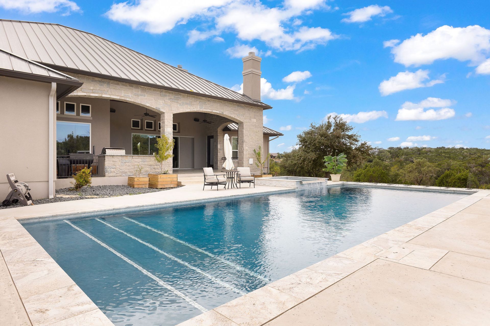 Modern house with a covered patio and a rectangular backyard swimming pool under a blue sky