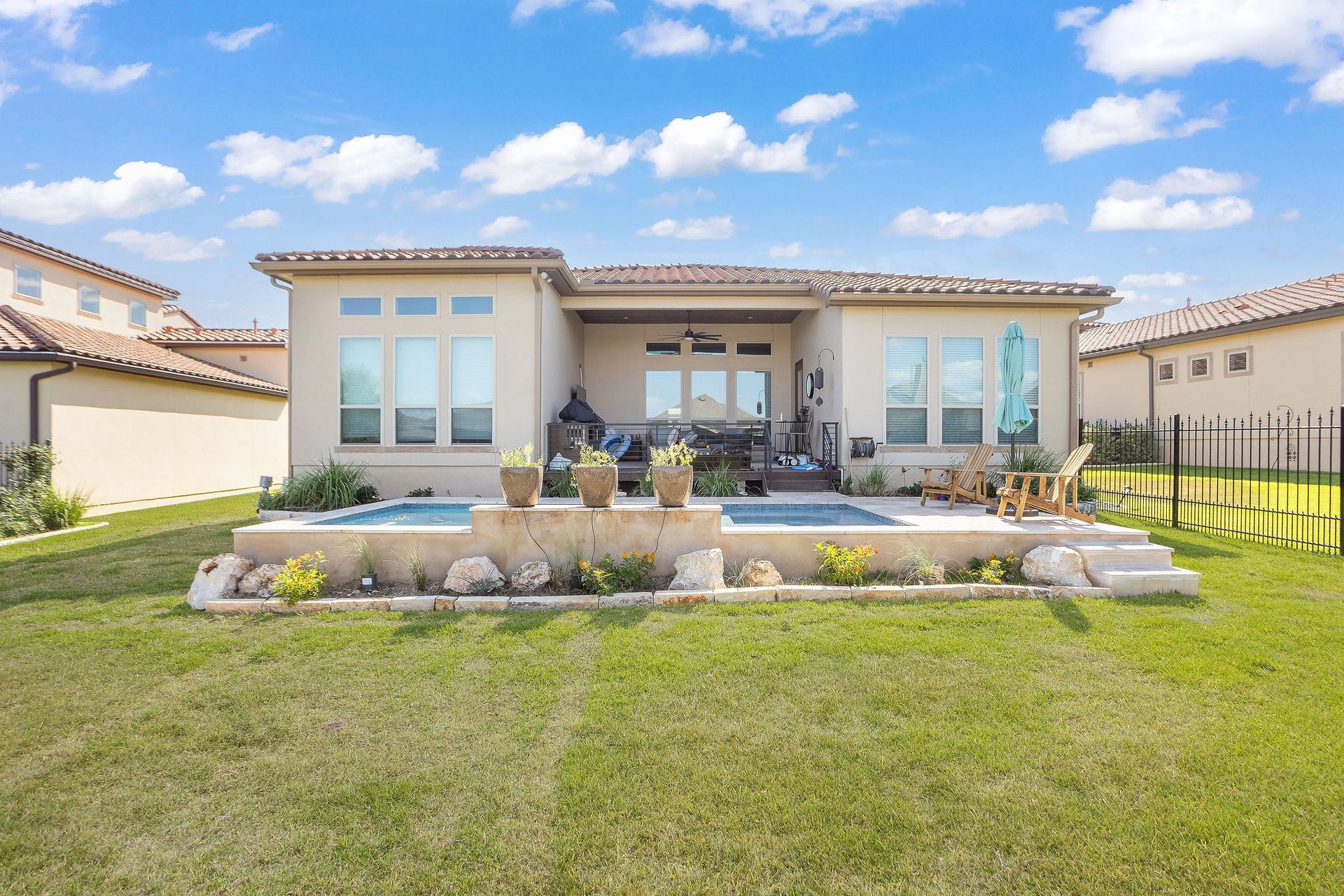 Modern beige house with a landscaped front yard, stone steps, and a bright blue sky