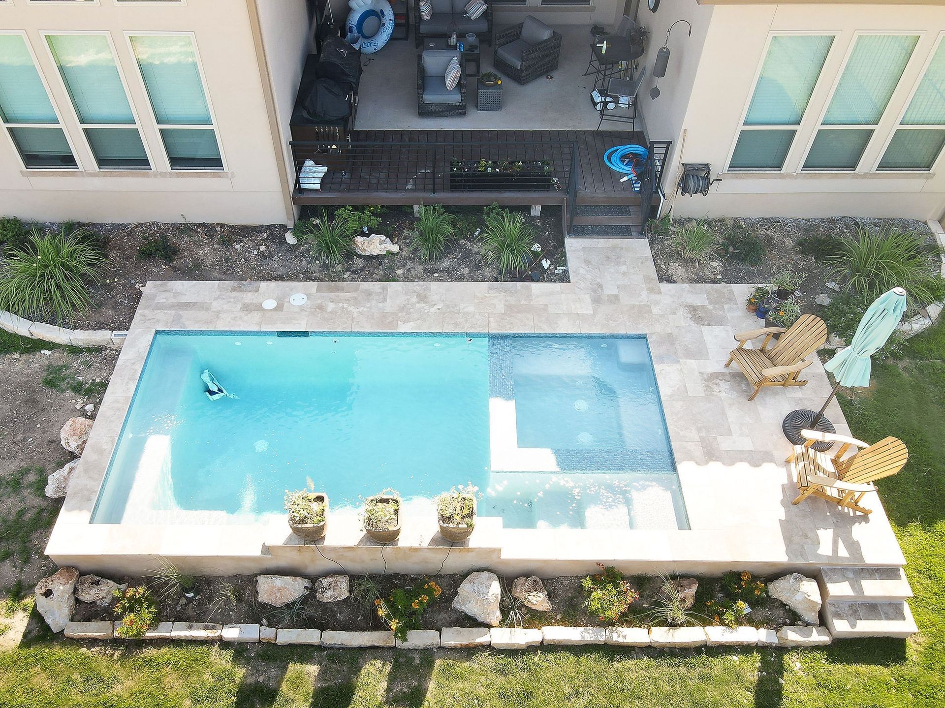 Small rectangular pool in a courtyard between buildings, with lounge chairs and potted plants nearby.
