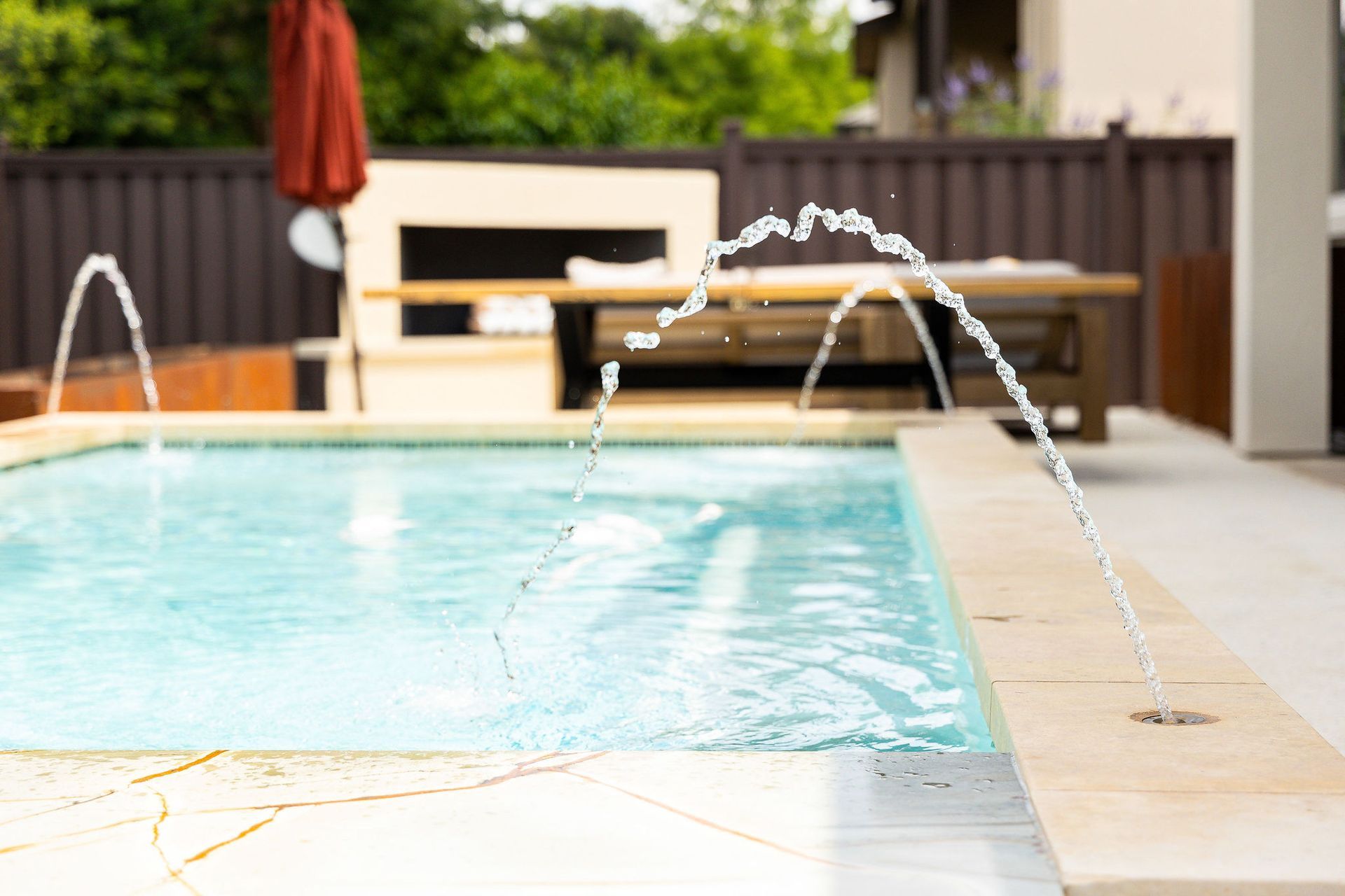 Backyard swimming pool with water jets arcing into the clear blue water