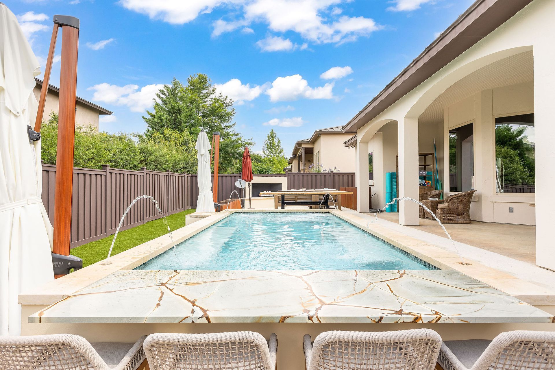 Backyard patio with a rectangular swimming pool, lounge chairs, and a covered outdoor seating area