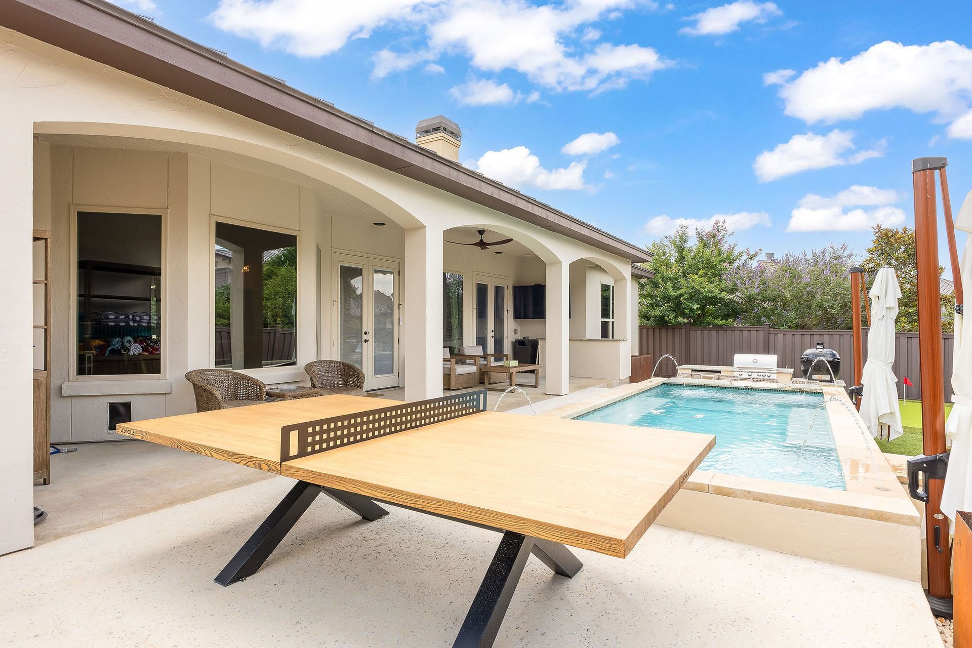 Backyard patio with lounge chairs beside a covered terrace and swimming pool