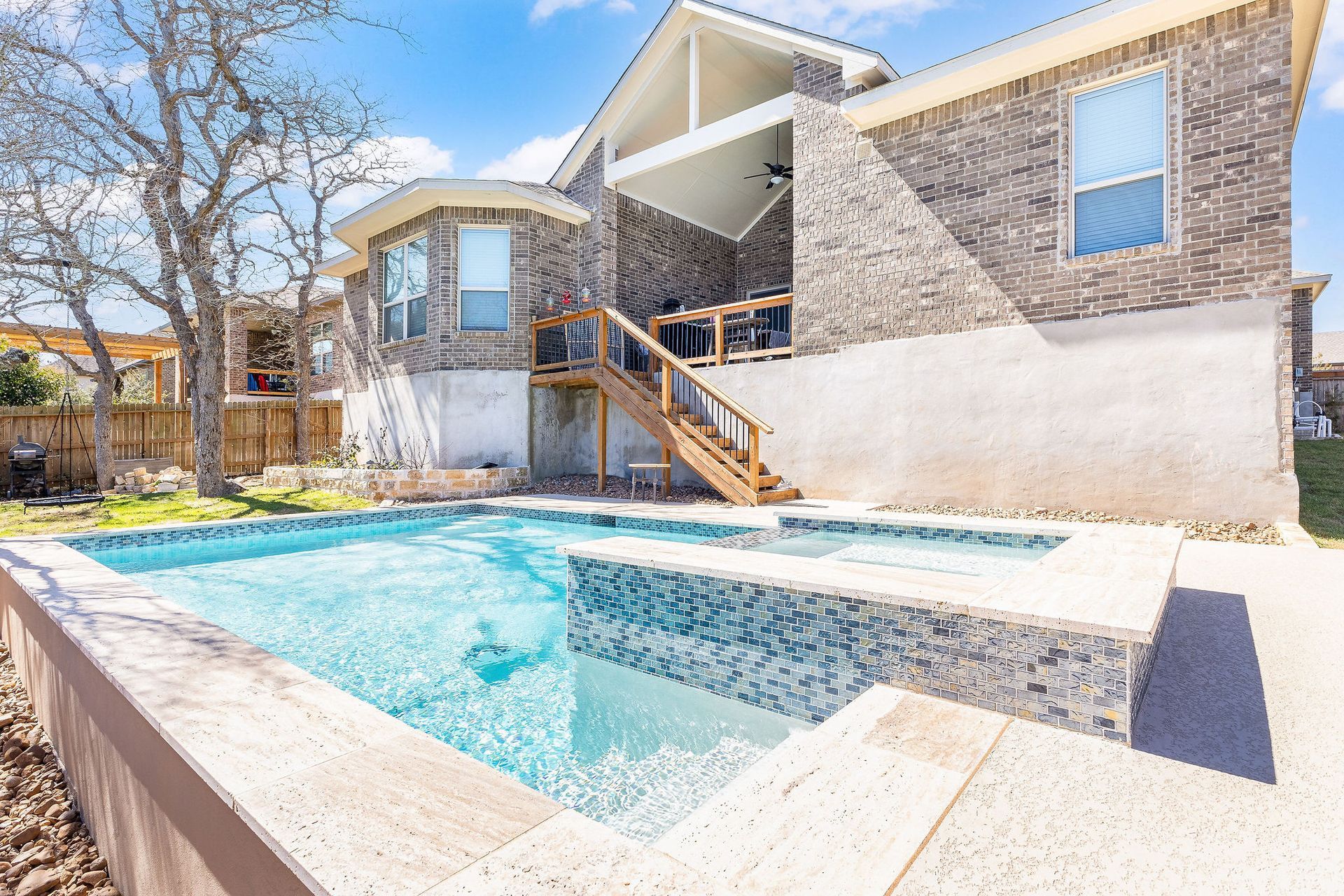 Backyard pool with hot tub beside a modern house and patio stairs