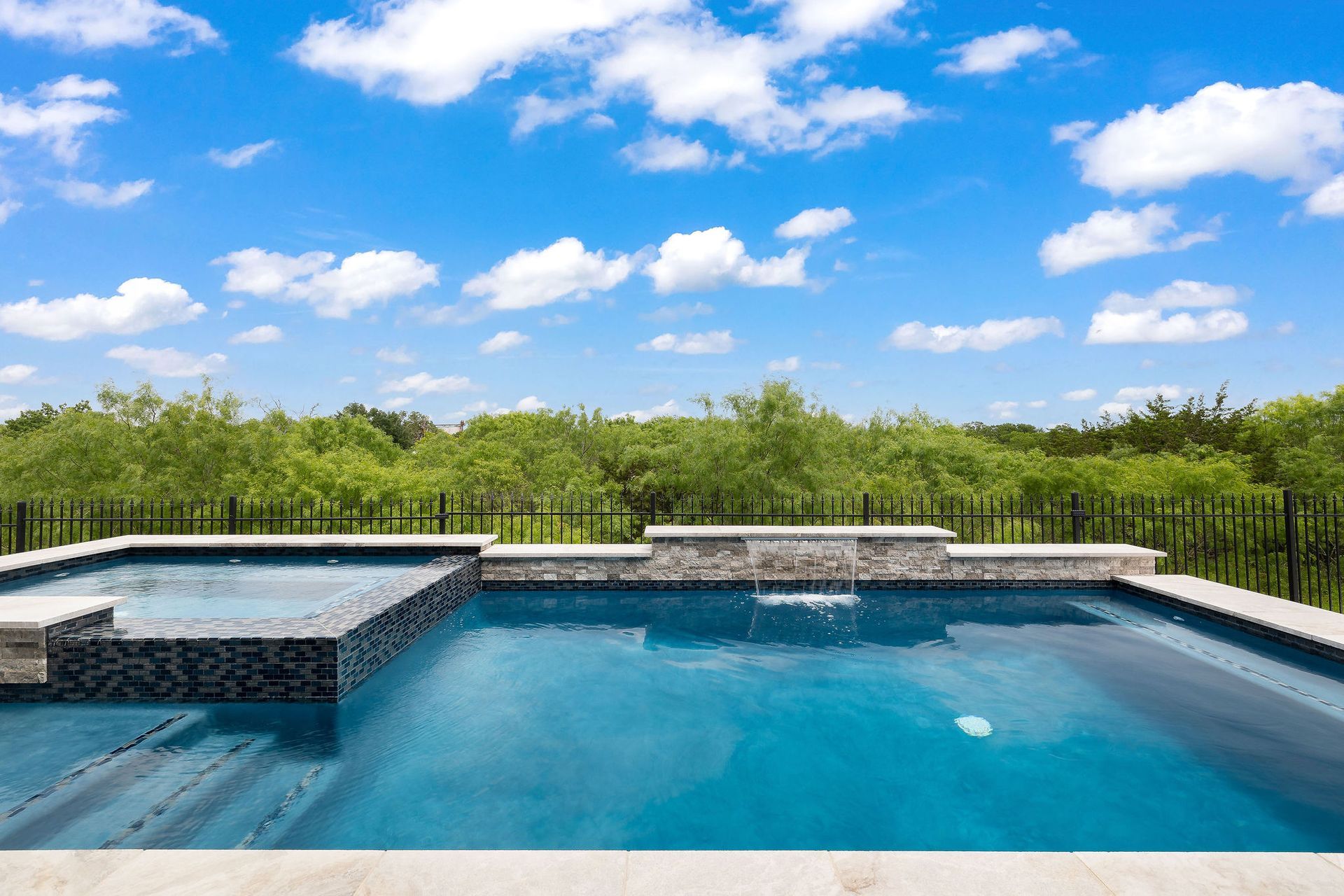 Modern backyard patio with a covered seating area and a rectangular swimming pool under a blue sky