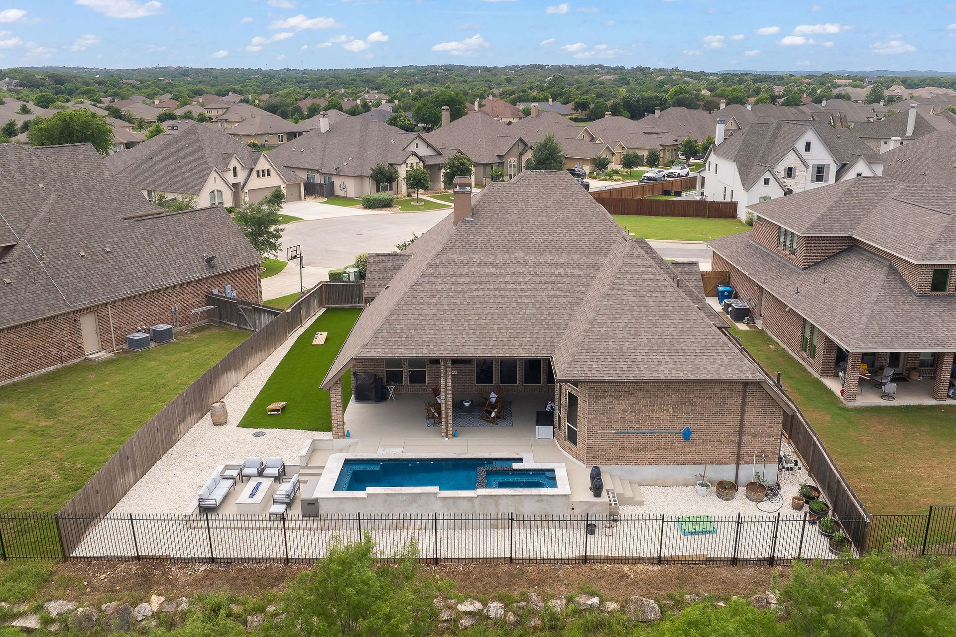 Aerial view of a suburban home with a backyard pool and surrounding fenced yard