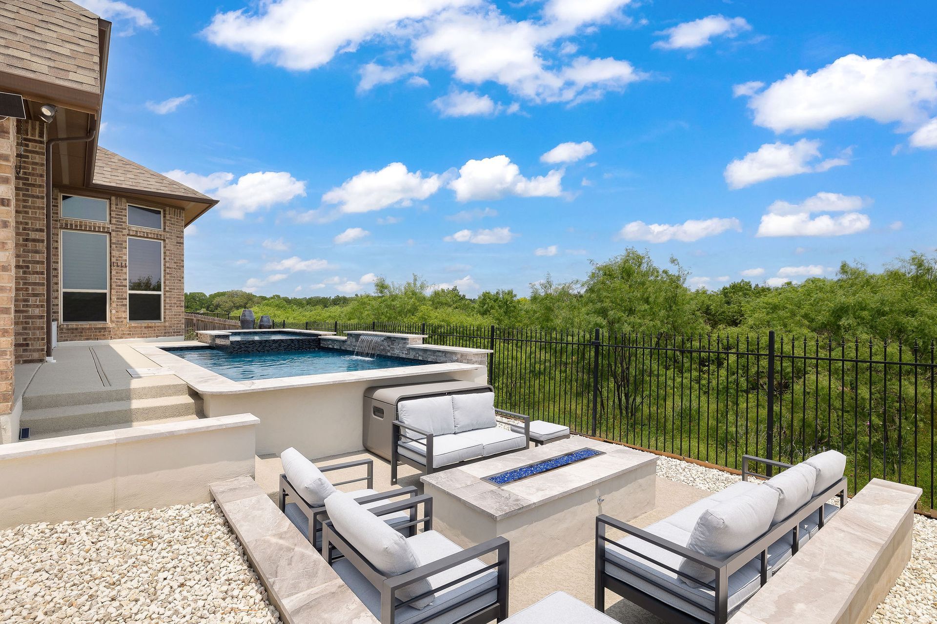 Backyard patio with cushioned seating, a fire pit, and an above-ground pool under a blue sky