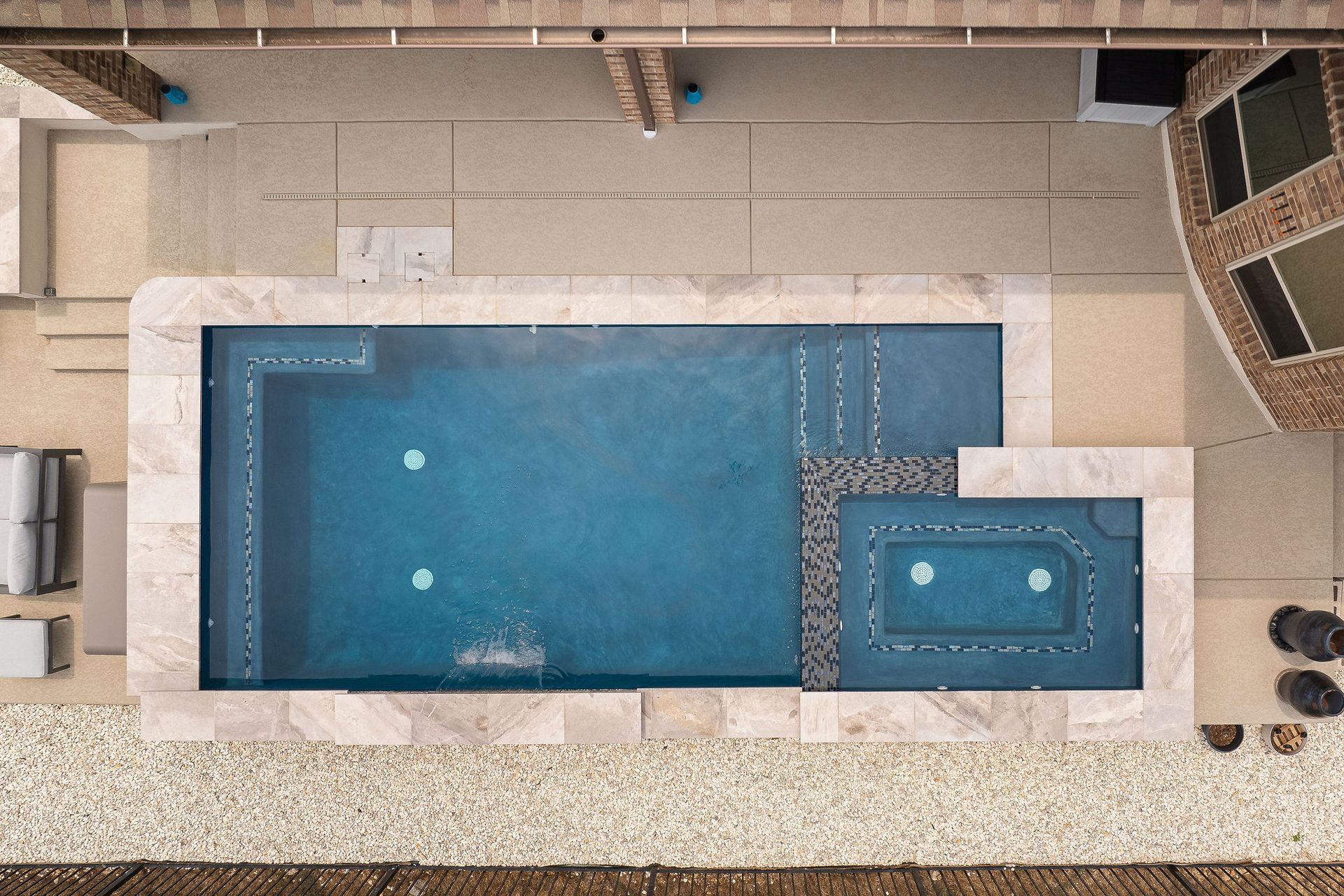 Top-down view of a rectangular backyard pool with a connected hot tub and surrounding patio.