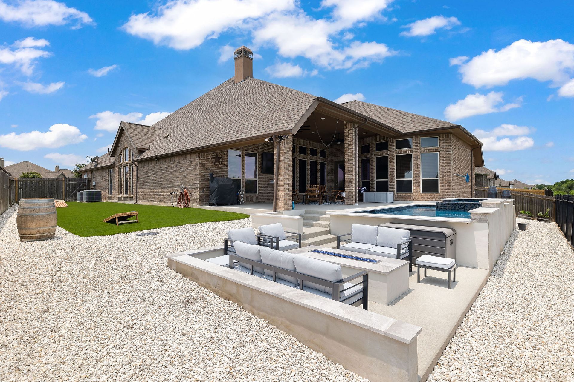 Stone house with a patio, outdoor seating, and a gravel yard under a blue sky