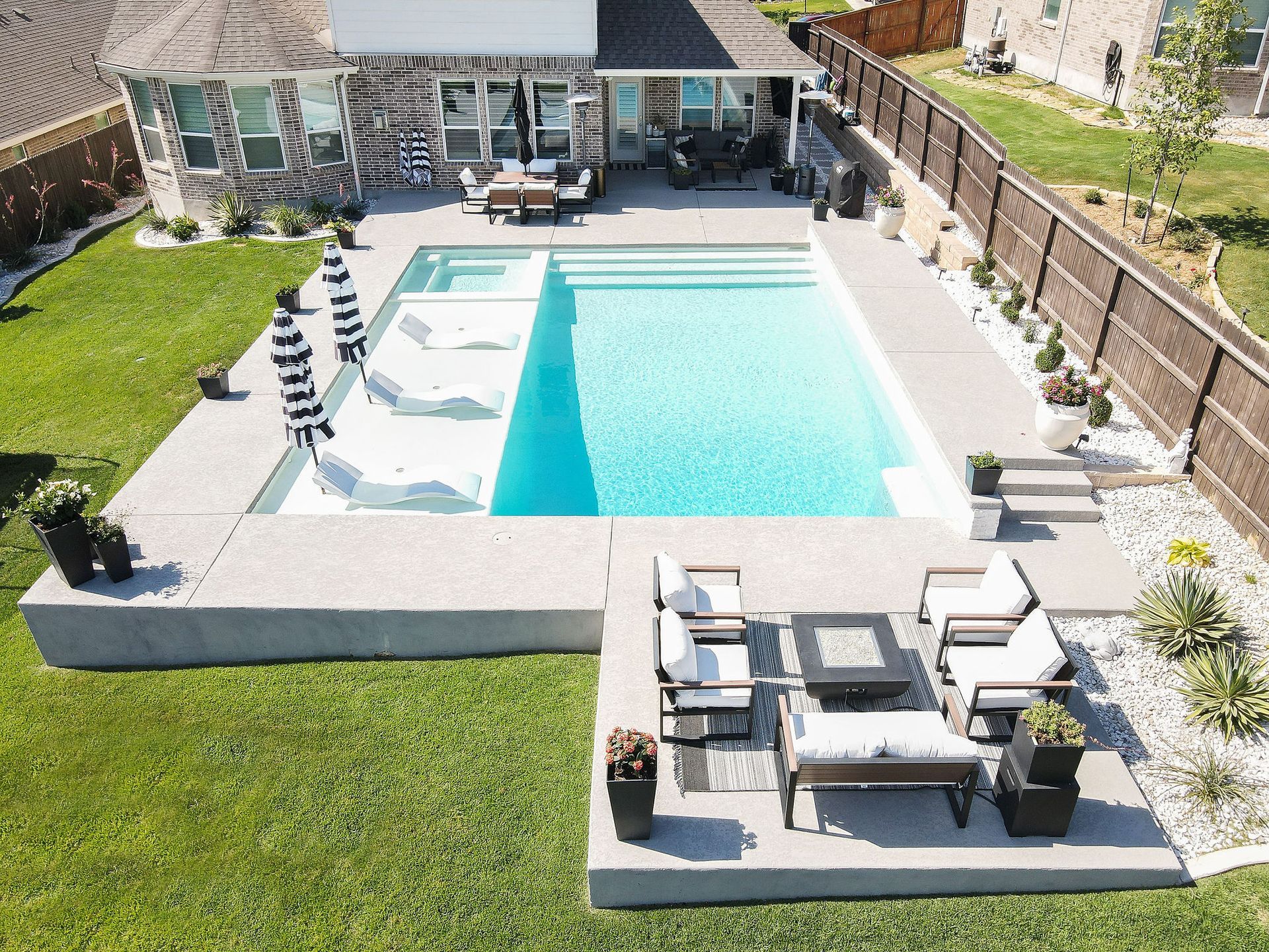 Backyard pool with a patio, lounge chairs, and green lawn beside a house