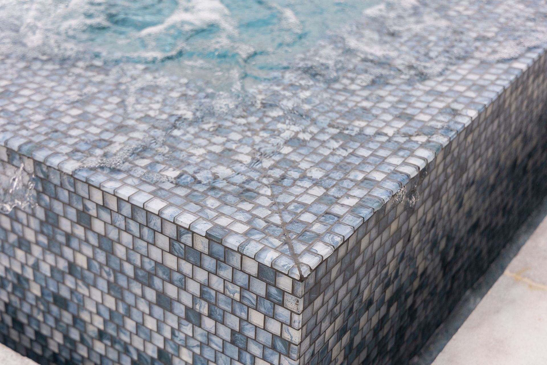 Corner of a stone-tiled water feature with rippling water on top
