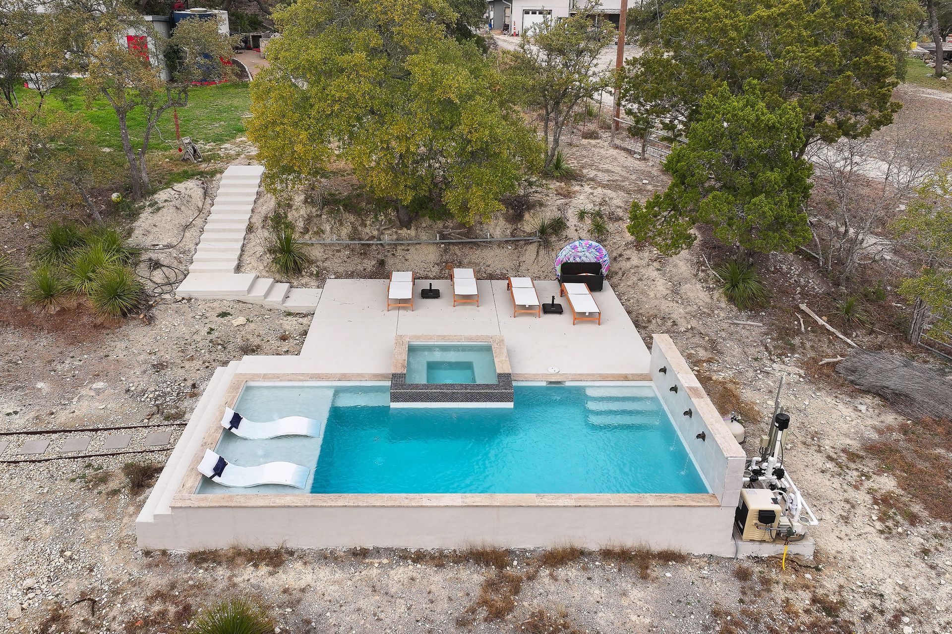 Modern backyard pool with lounge chairs, trees, and a sunset sky