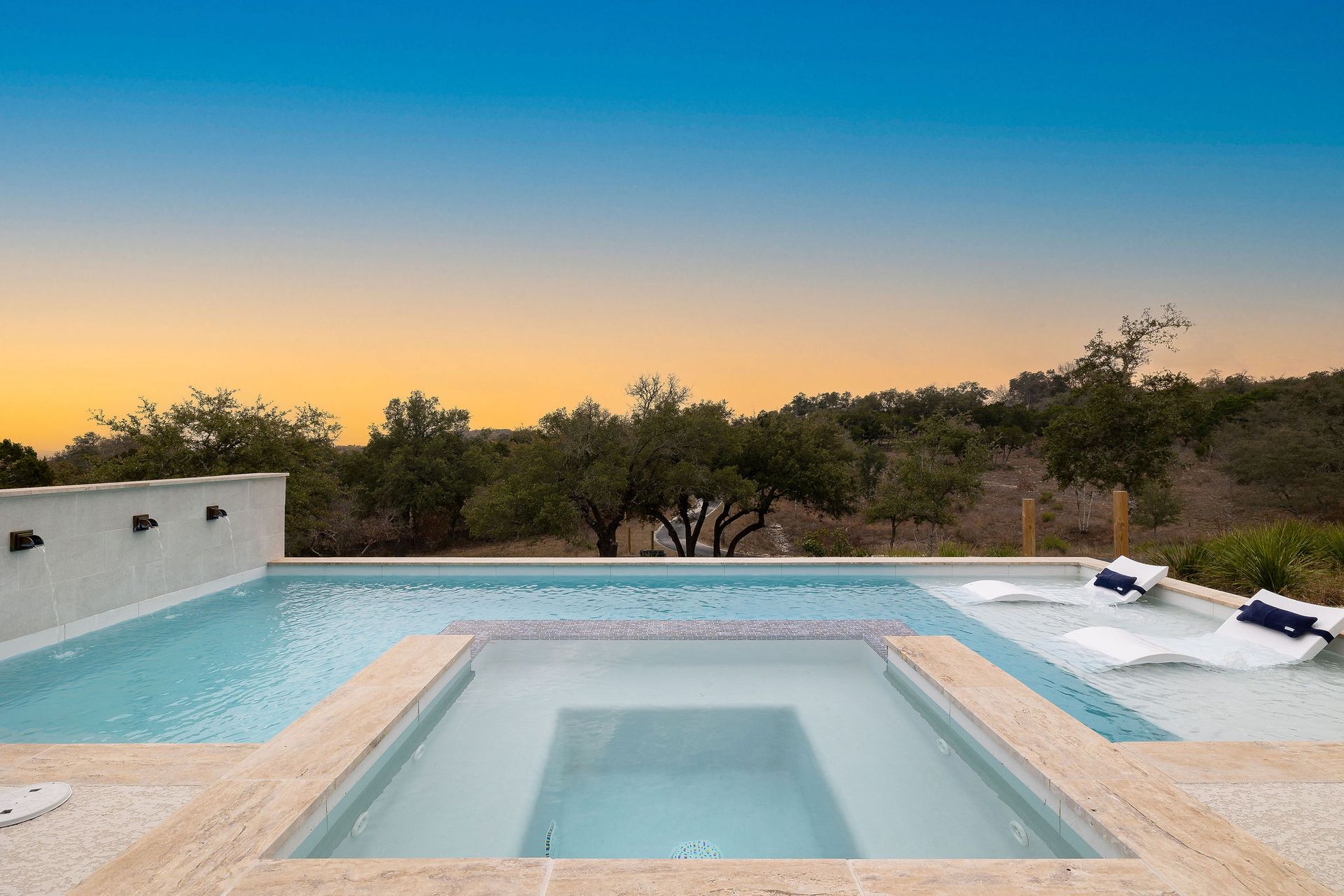 Modern backyard pool with lounge chairs, trees, and a sunset sky