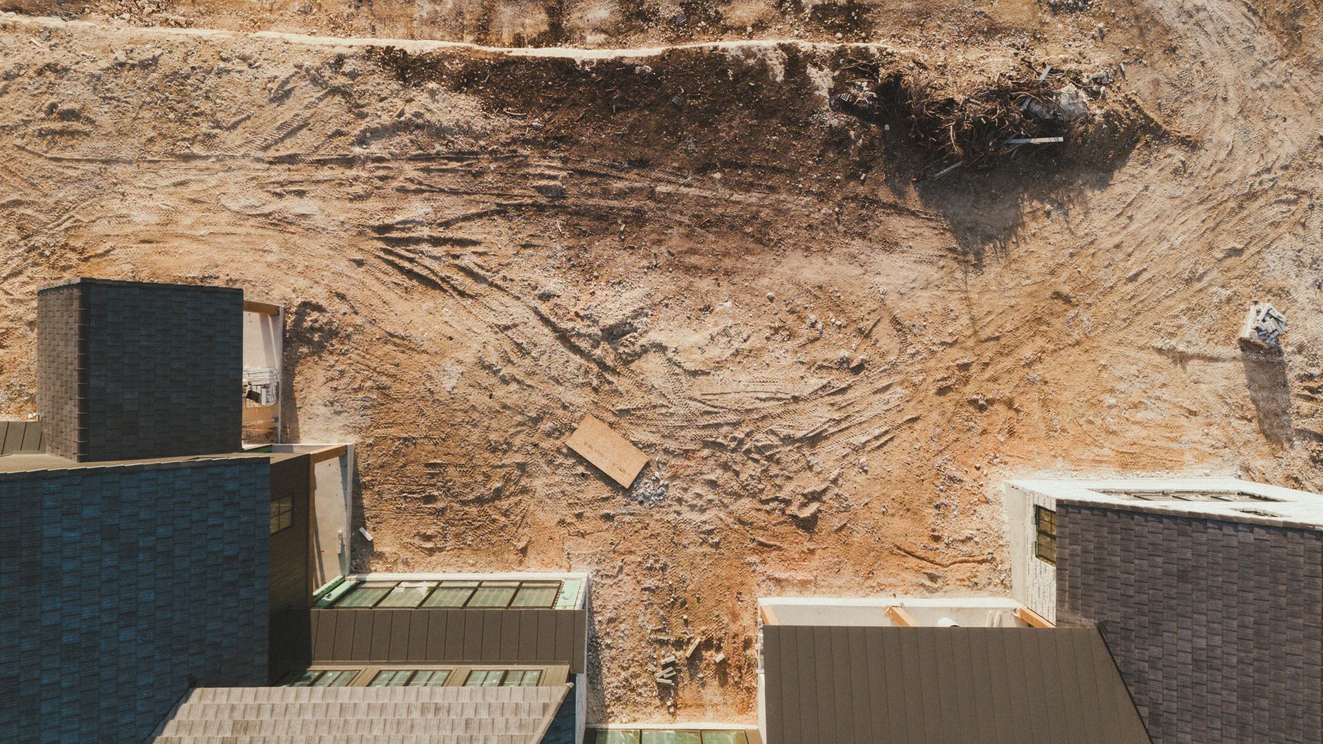Rocky quarry wall behind stacked gray and tan cargo containers in bright sunlight