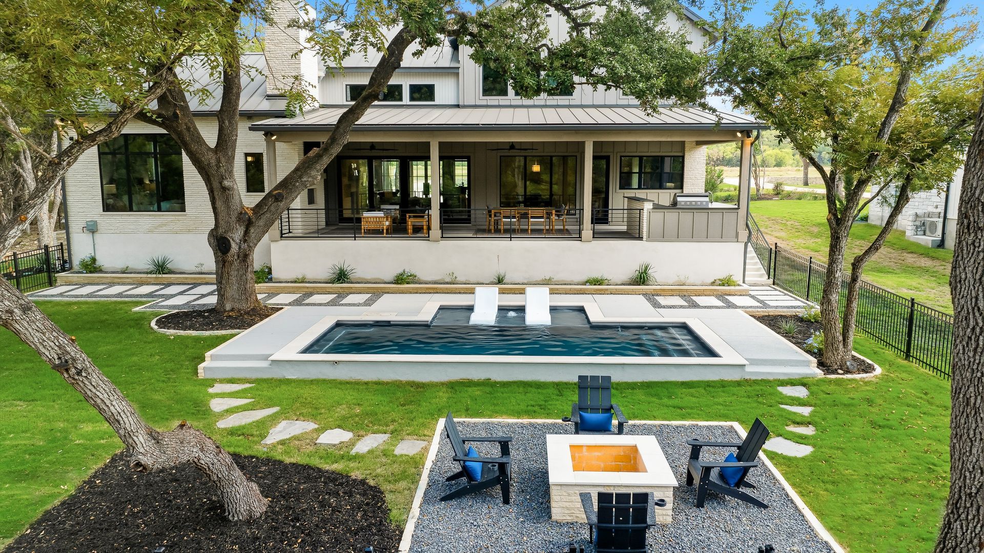 Modern backyard with a pool, patio seating, and a house with a covered porch