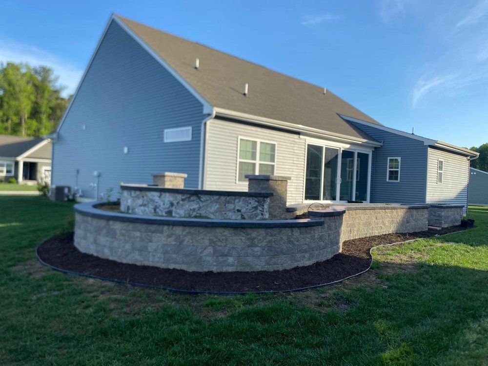 The back of a house with a stone wall in front of it.
