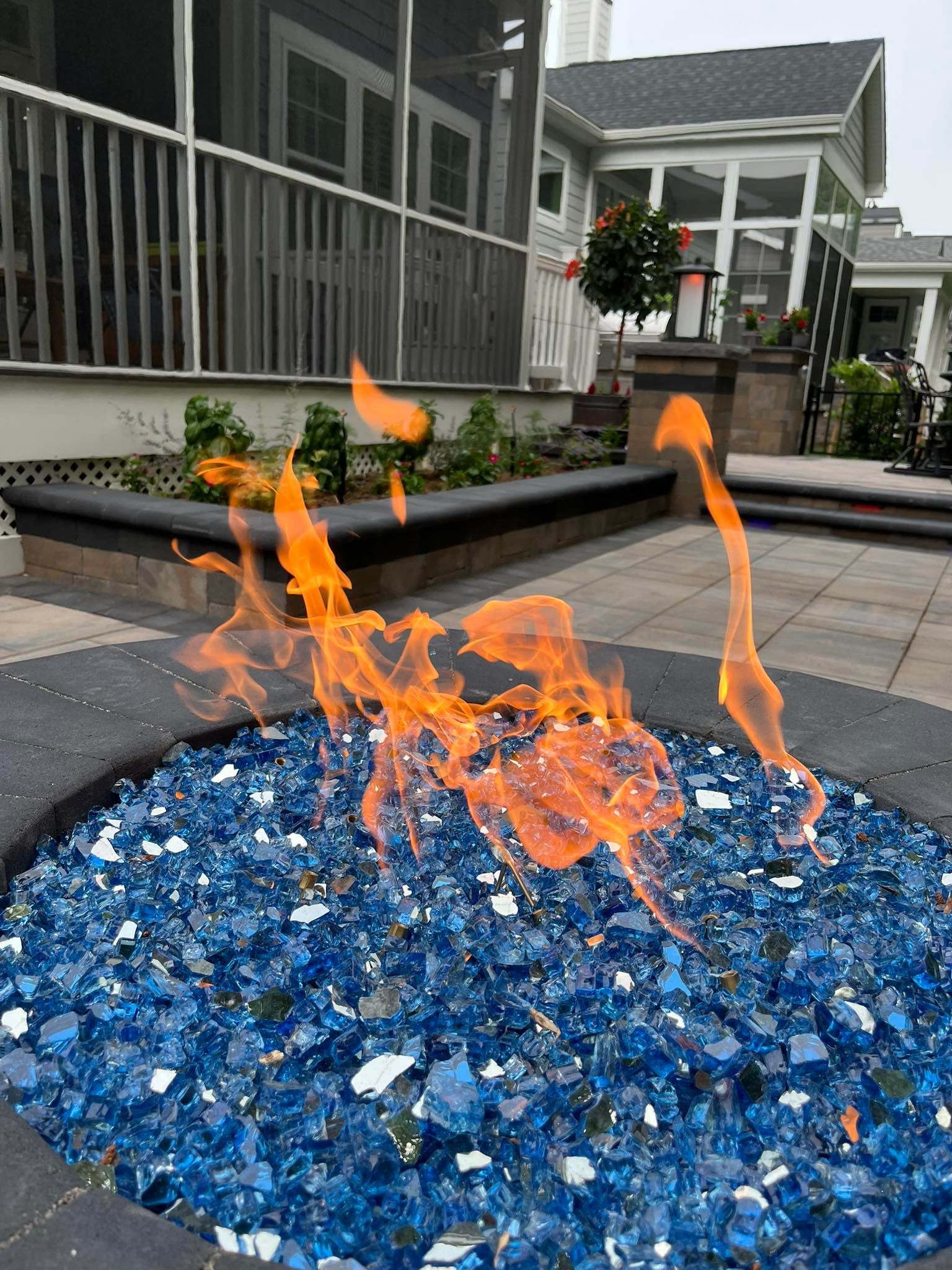 A fire pit filled with blue glass rocks and flames.