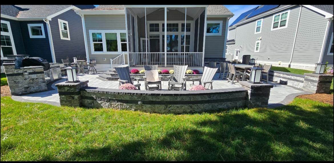 Backyard patio with lounge chairs and fire pit in front of a house and screened porch