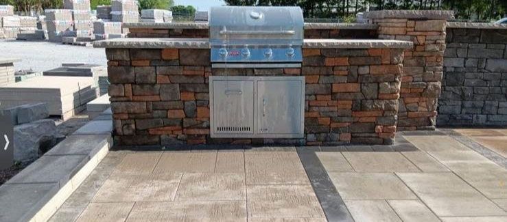 Brick wall-mounted public outdoor grill on a rooftop terrace with paved stone flooring