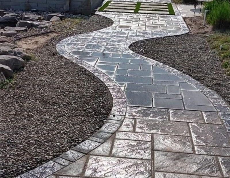 Winding stone garden path bordered by gravel and rocks, leading to steps in the distance