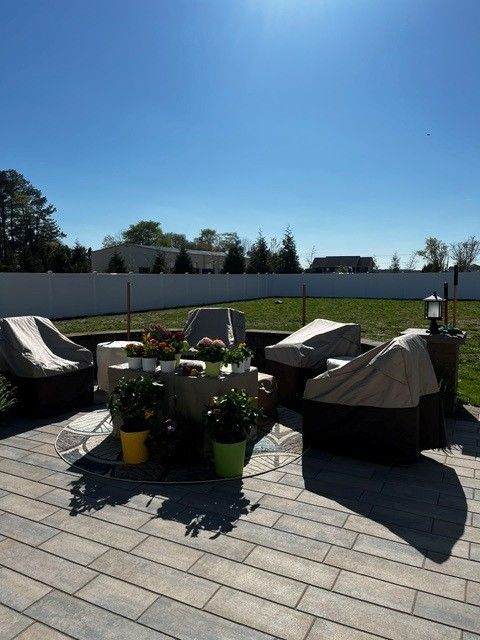 Patio seating area with covered outdoor furniture, potted plants, and a clear blue sky