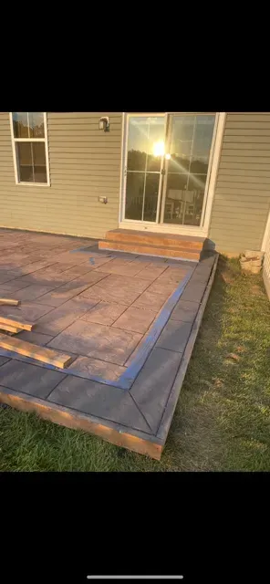 Backyard deck with fresh blue trim and steps beside a house wall and sliding glass door at sunset