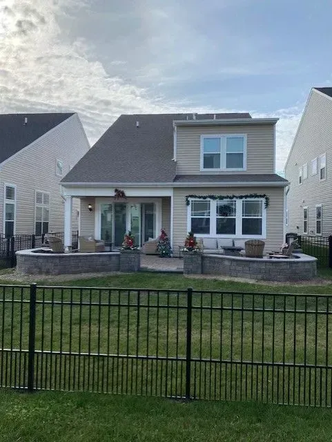 Suburban house with front porch and stone planters behind a black metal fence