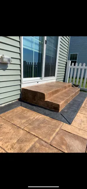 Wooden step platform leading to sliding glass door beside a white fence and tan siding