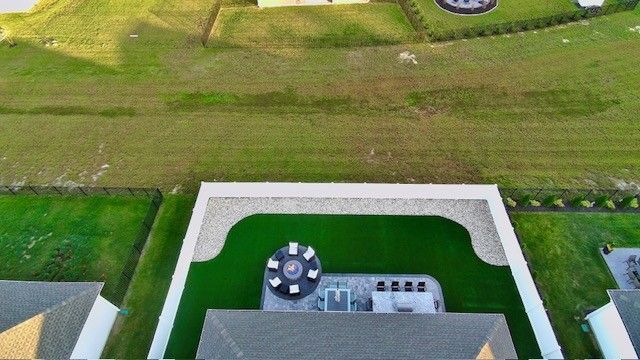 Aerial view of a modern house patio with a round table, white walls, and green lawn nearby.