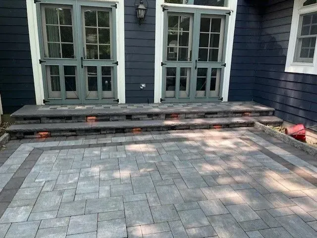 Back patio with gray pavers and three wide steps leading to blue French doors