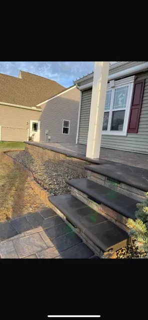 Front steps and porch of a beige house with cream columns and maroon shutters at sunset.