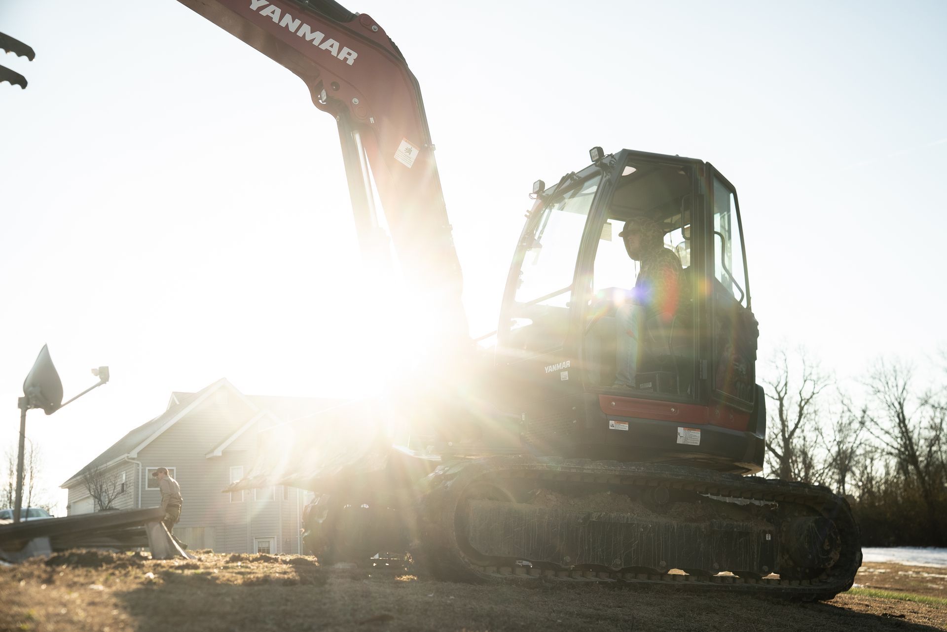 Excavator silhouetted by bright sun at a construction site