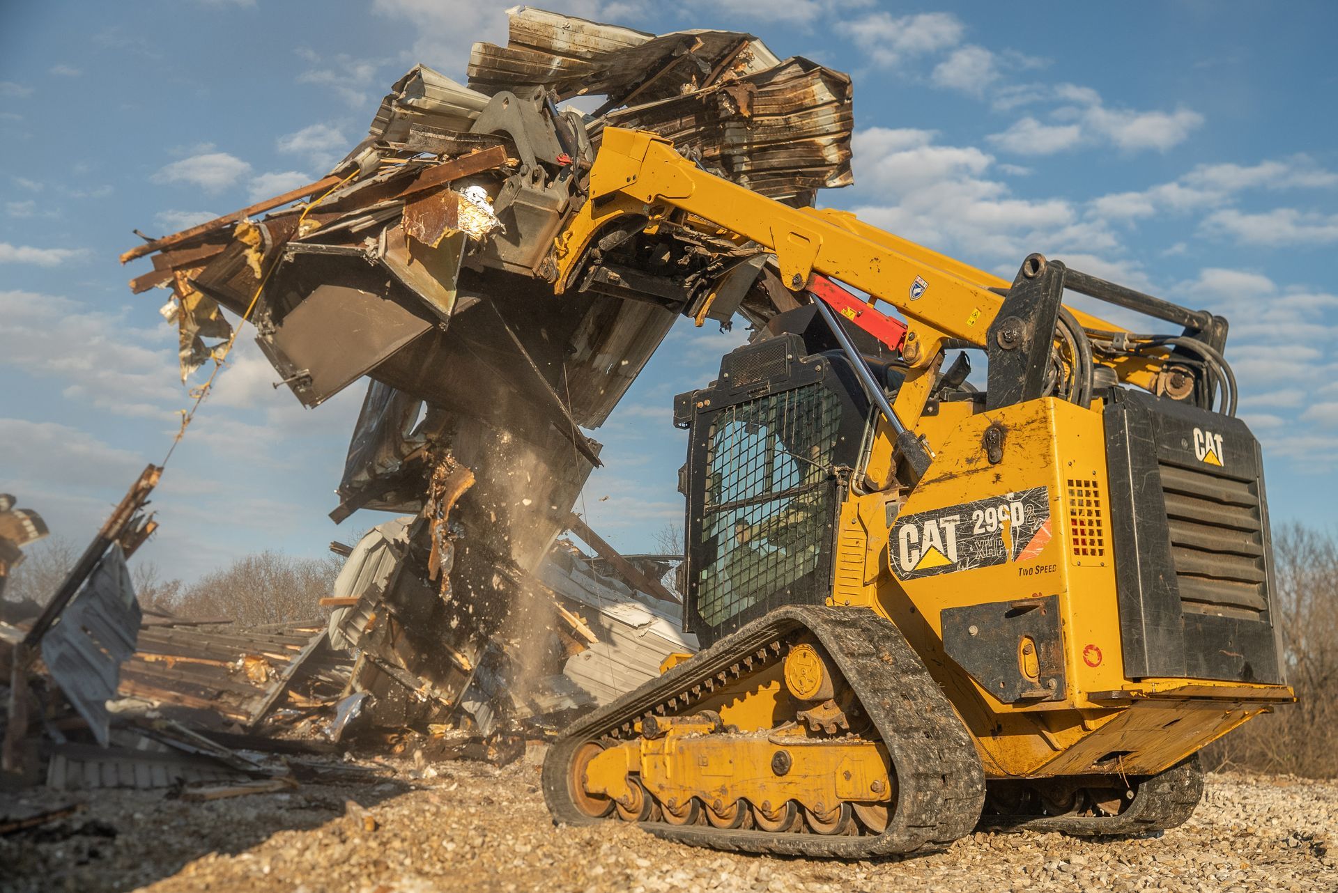 Yellow excavator demolishing a collapsed building, with debris and dust in a construction site