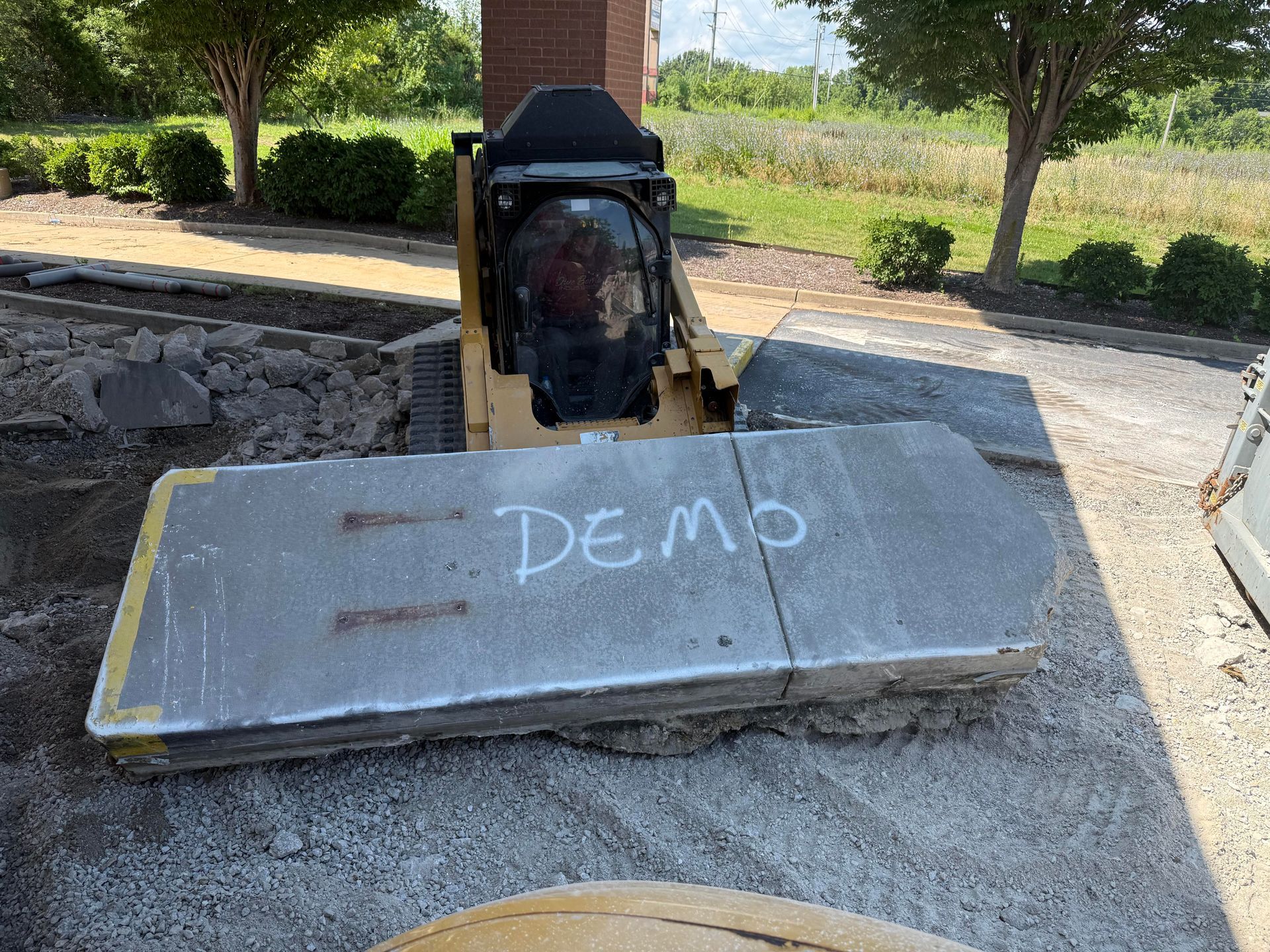 Concrete slab with “DEMO” painted on it in front of a machine outdoors