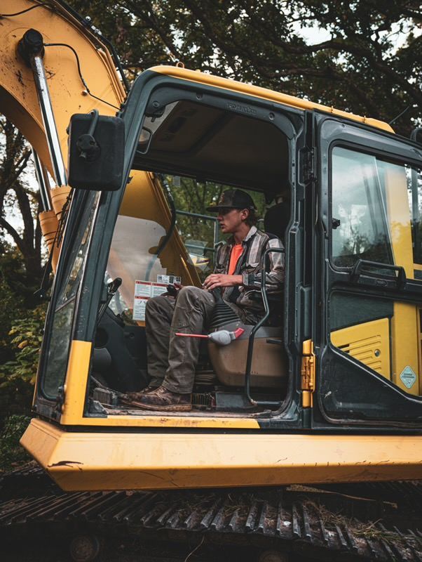 Operator seated inside a yellow excavator cab on a work site