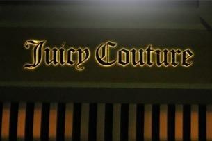 Juicy Couture logo in gold lettering on a dark background with vertical orange stripes