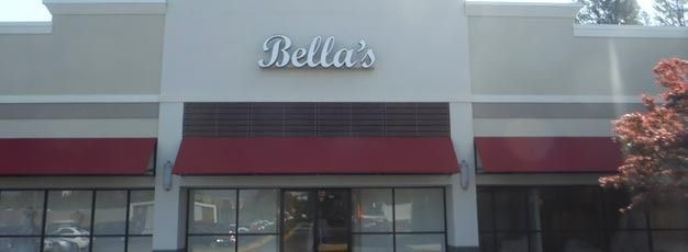 Storefront with the sign “Bella’s” above a maroon awning and glass entrance