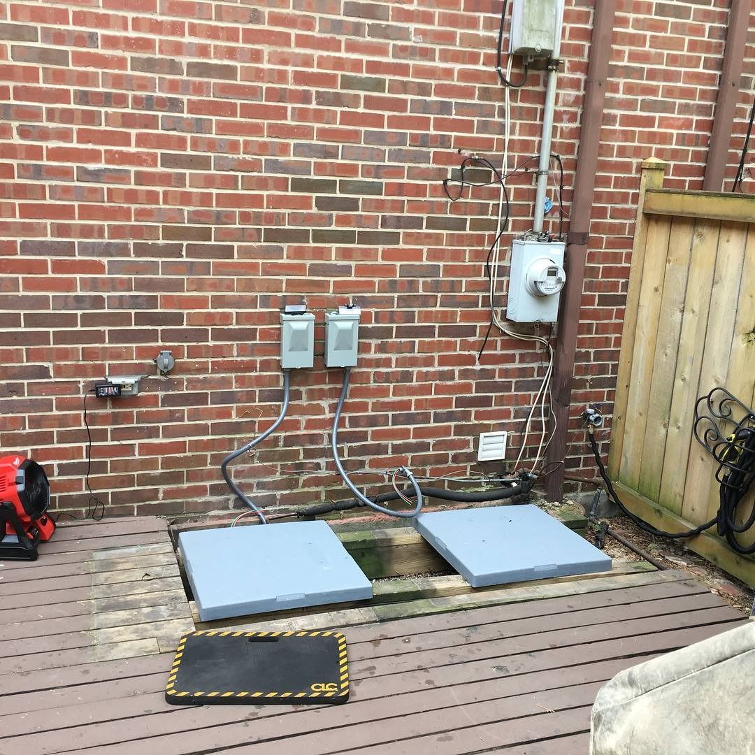 Brick wall with two gray covers on a deck, electrical boxes, and a utility meter.