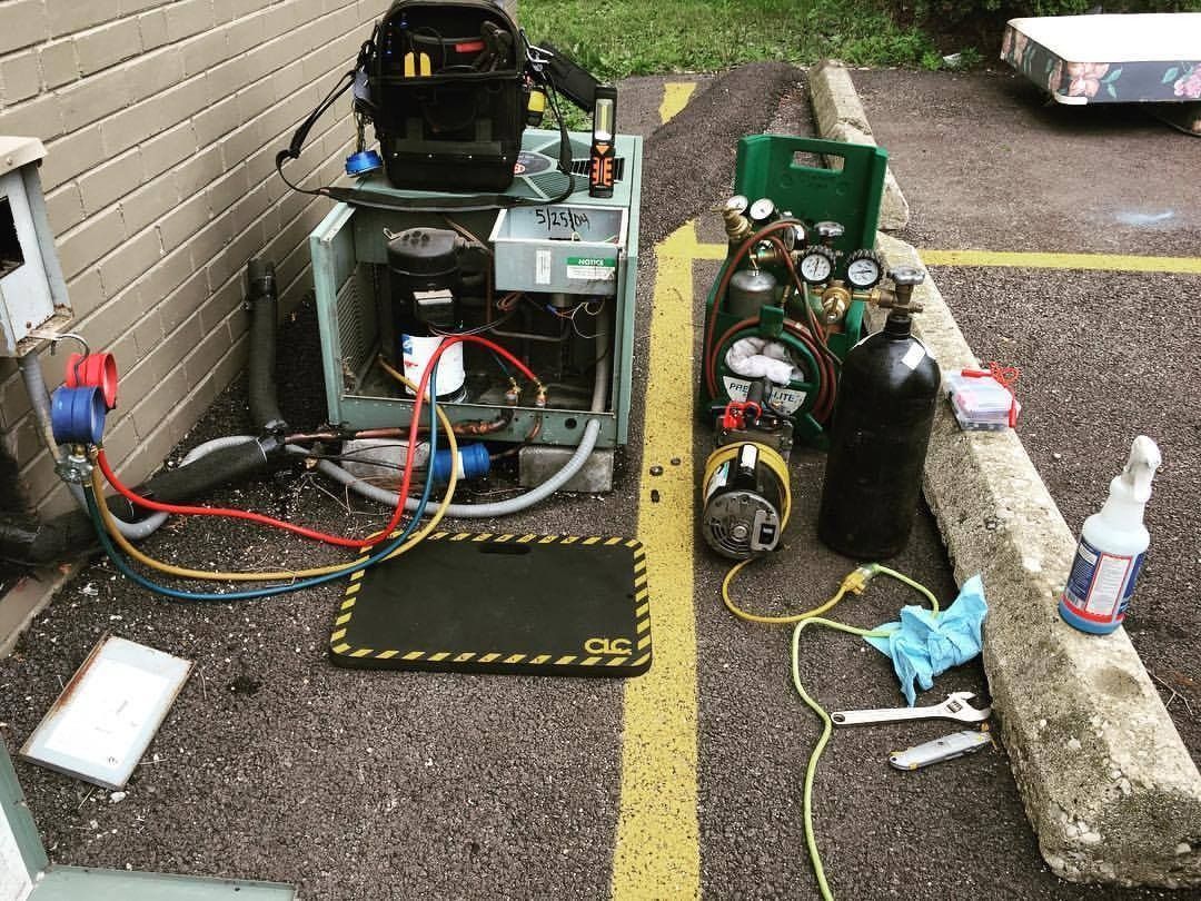 HVAC technician's tools and equipment set up outdoors next to an air conditioning unit for repair.