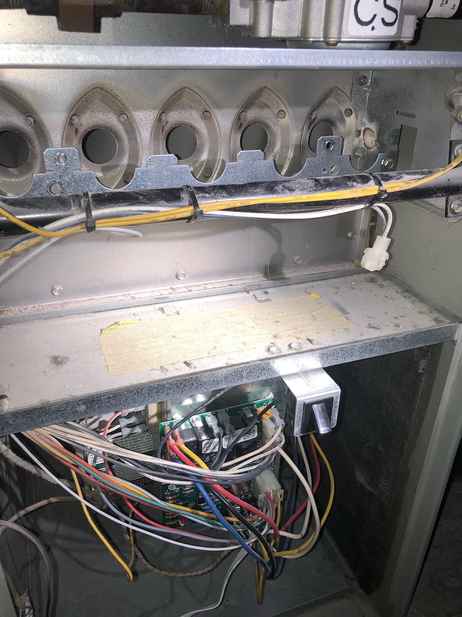 Furnace interior showing burners, wiring, and circuit board.