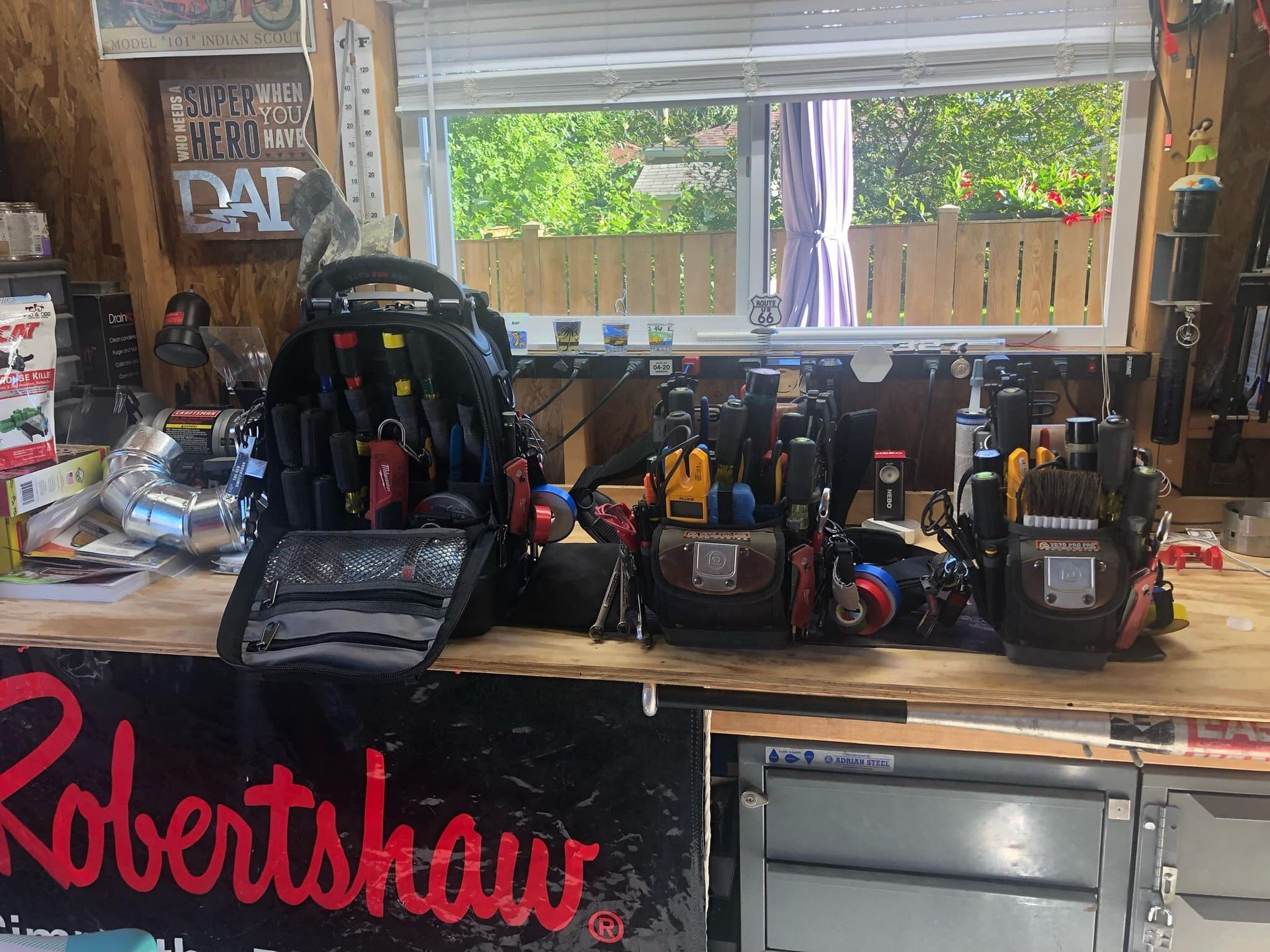 Tool bags and tools on a workbench in a garage setting with a window in the background.