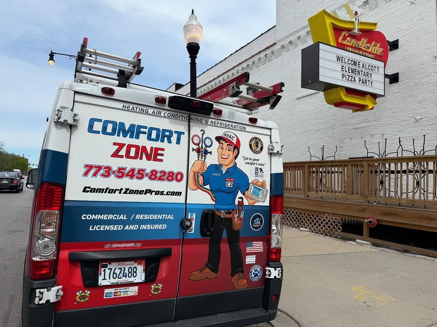 Comfort Zone van parked near a Candlelite restaurant.  The van has a worker cartoon graphic and contact info.