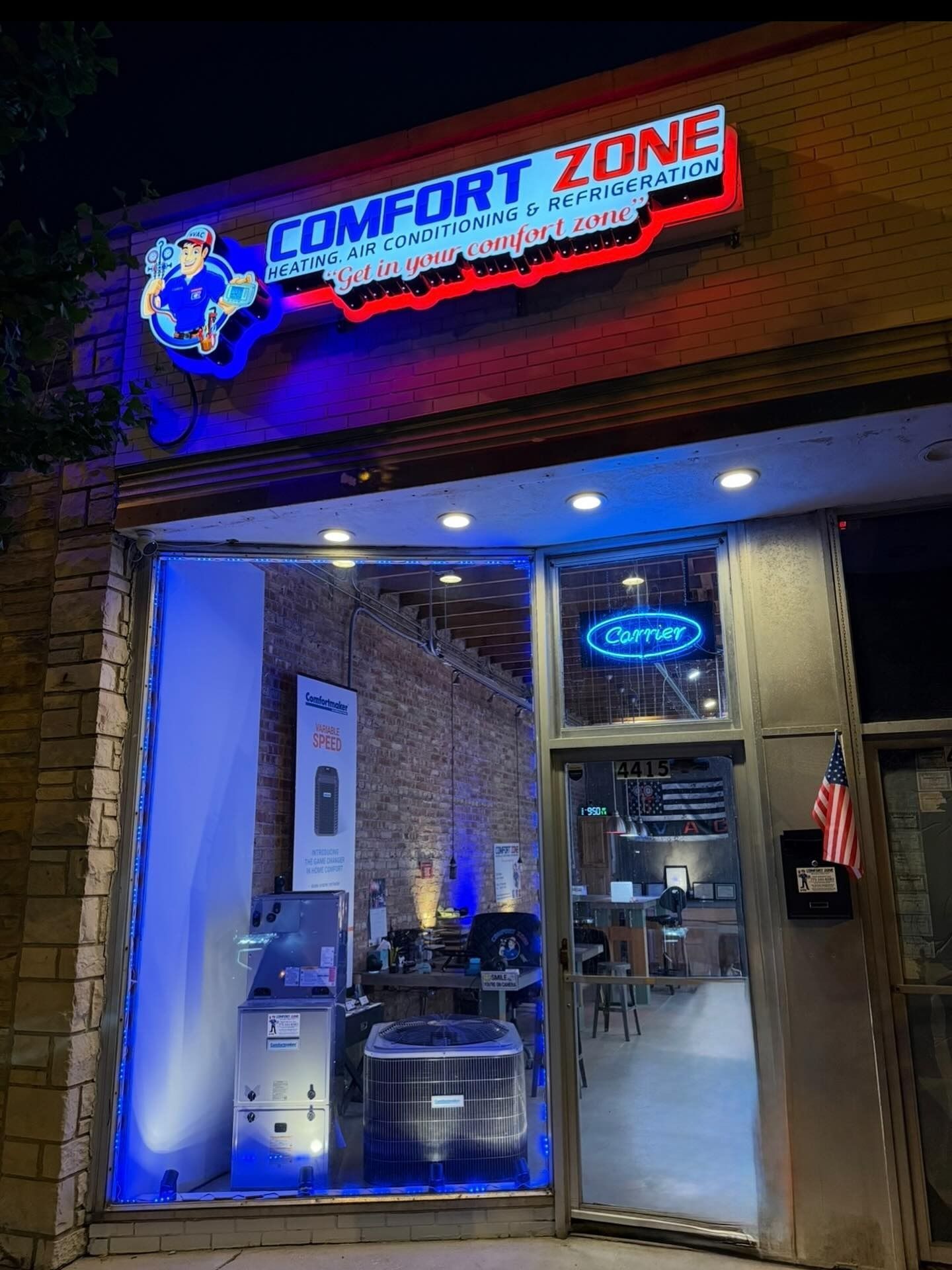 Exterior of Comfort Zone HVAC repair shop at night, with illuminated sign and blue lighting.