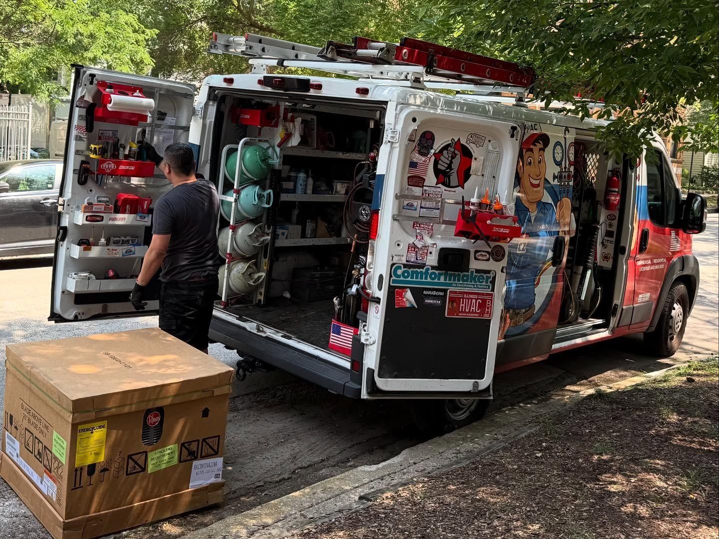 Service van with open doors, worker unloading a box; tools and equipment inside.