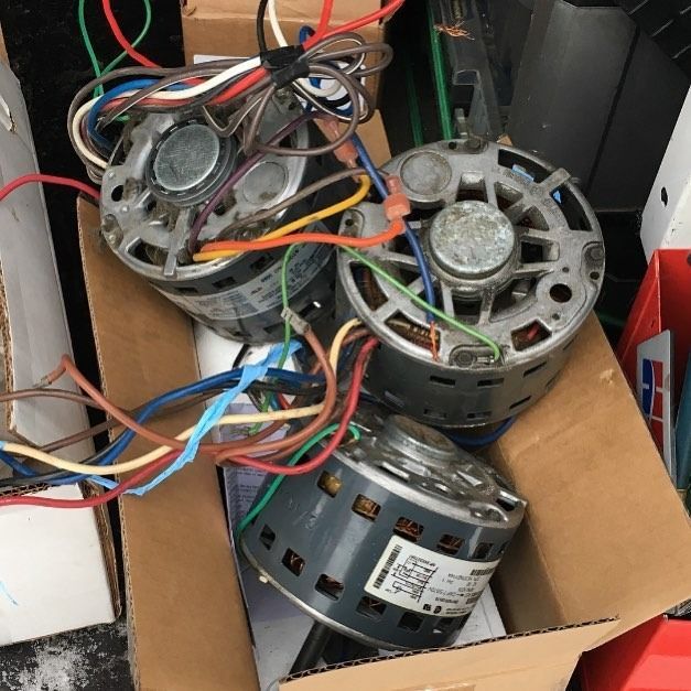 Three electric motors with colored wires in a cardboard box.