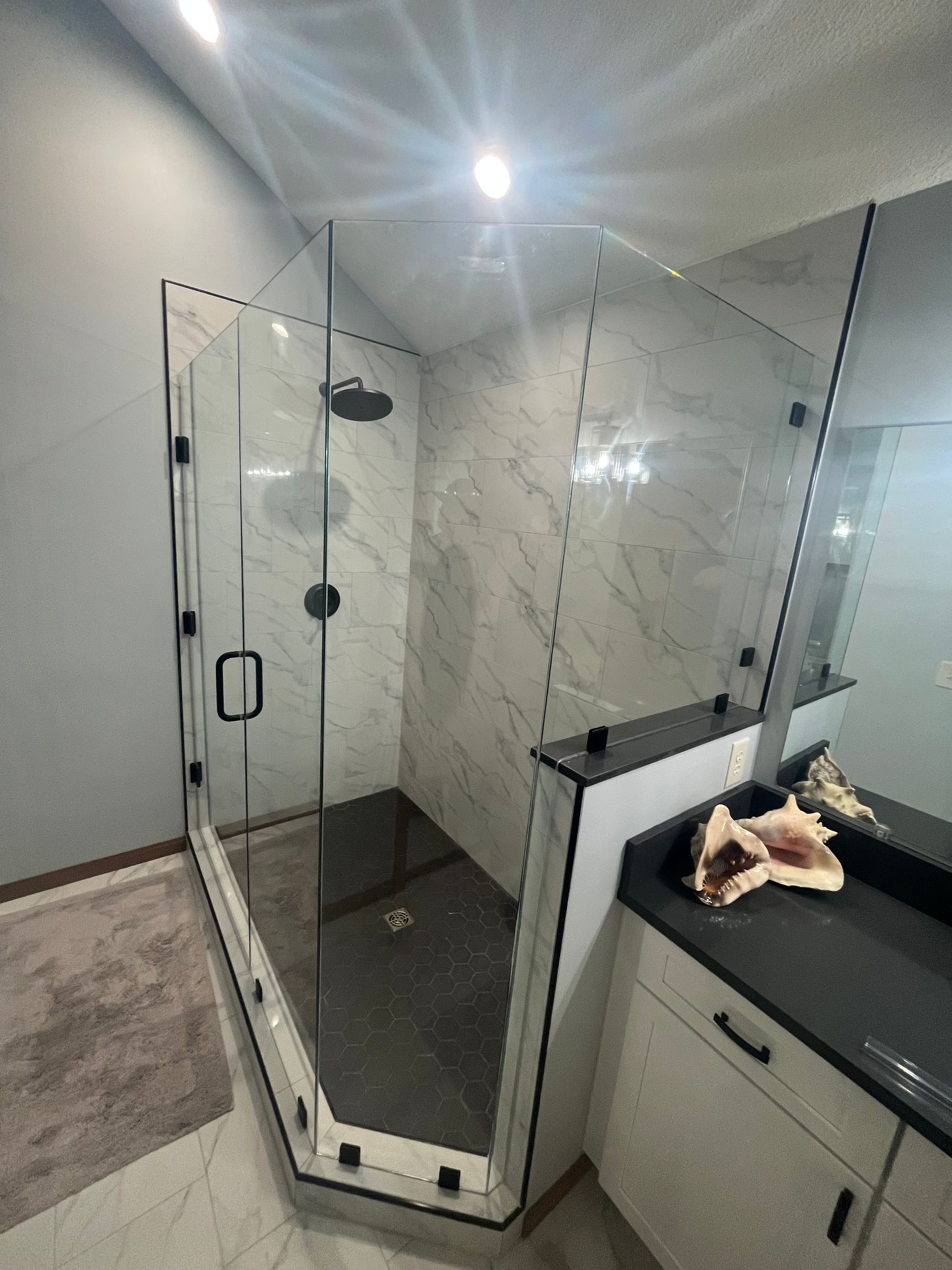 A bathroom with a walk in shower and a sink.