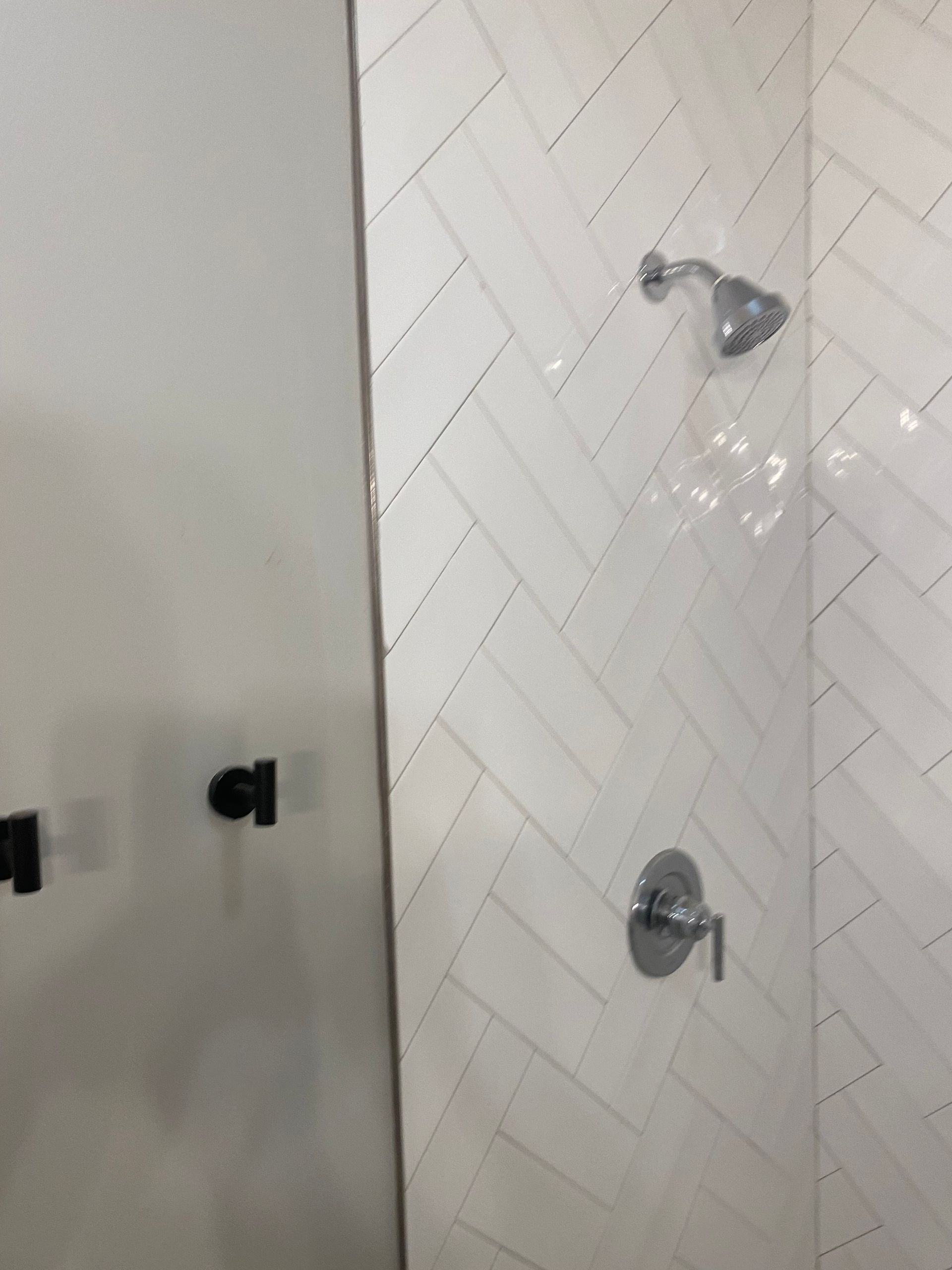 A bathroom with white tiles and a shower head